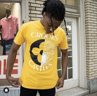 a man wearing a yellow t - shirt in front of a store